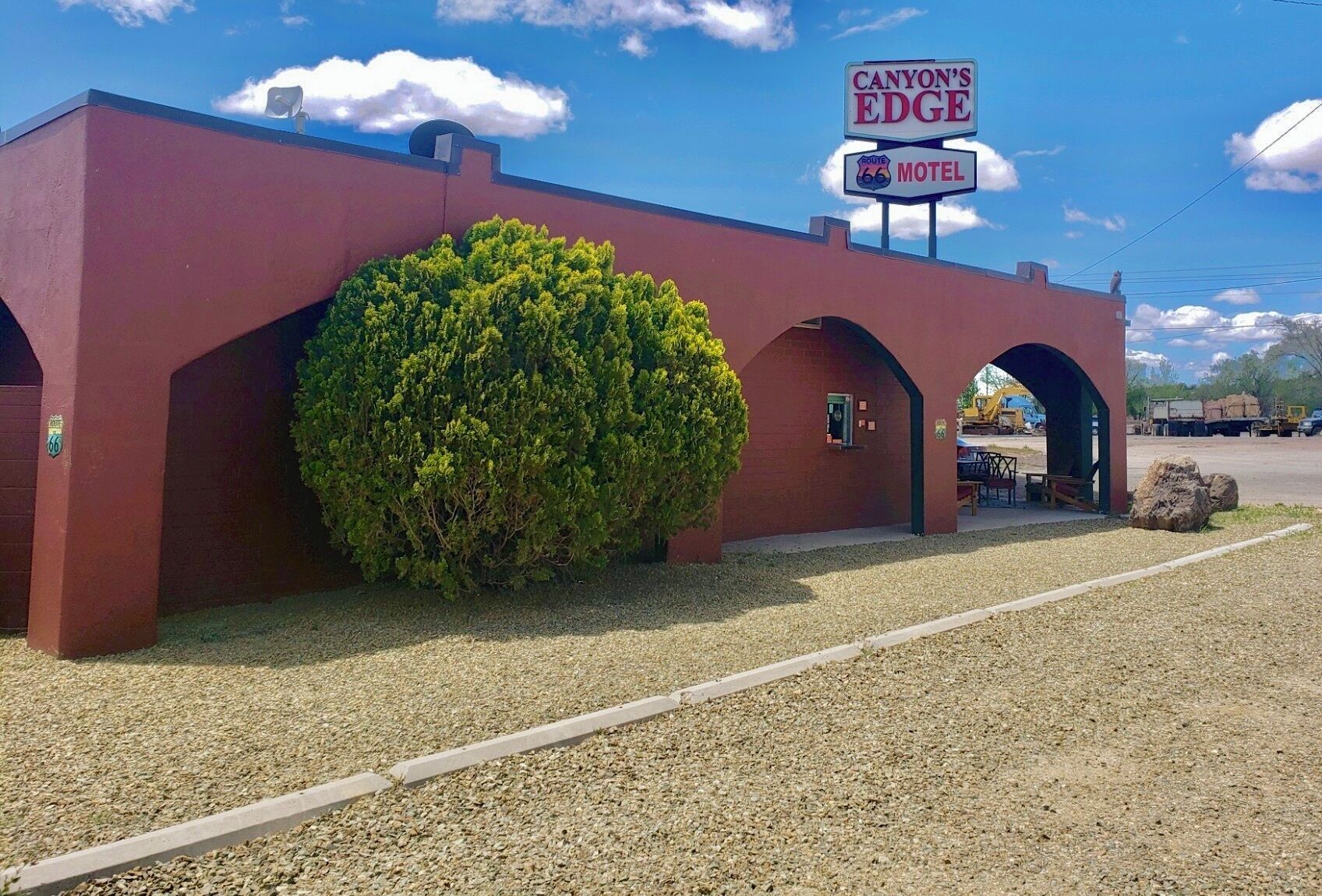 A red building with a sign for Canyon's Edge Motel, a large bush, and a gravel driveway.