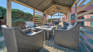 An outdoor patio with wicker furniture, a grill, and a covered area with a metal roof. - Canyons Edge Route 66 Motel (Ash Fork)