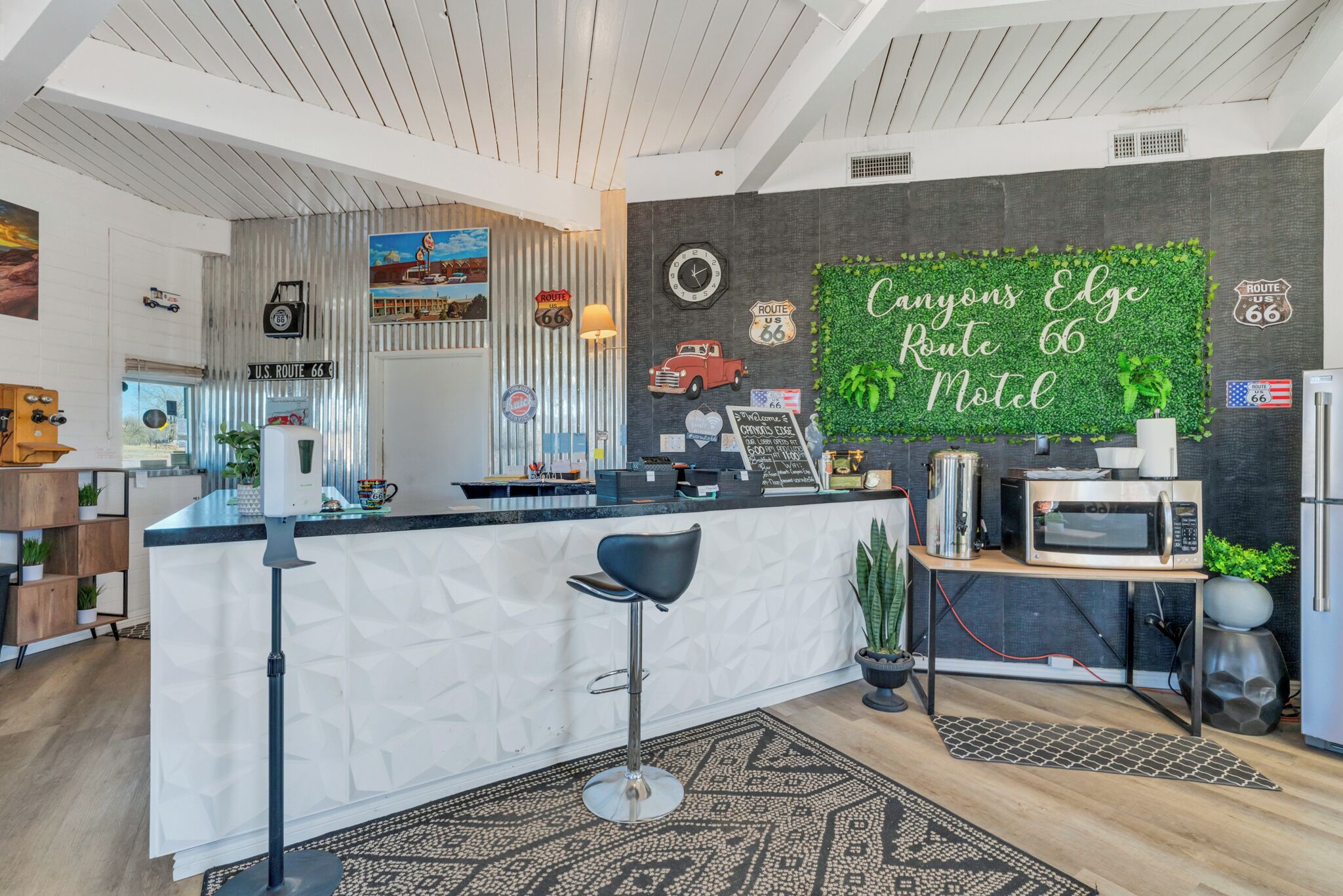 A reception area with a counter, a clock, Route 66-themed decorations, a green wall, and a bar stool.