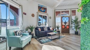 A spacious living room with a sofa, a coffee table, and a large window. - Canyons Edge Route 66 Motel (Ash Fork)