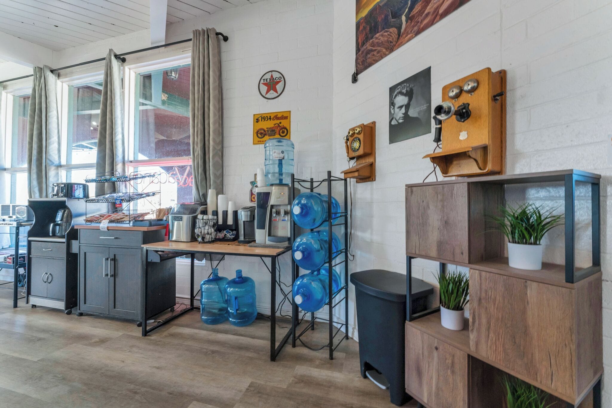 Cozinha com máquina de café, dispensadores de  água e armário de madeira com plantas.