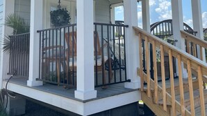 A covered porch with a wooden railing, a small window, and a door. - Riverfront Tiny House- Fishing & Kayaking (Strawberry Plains)