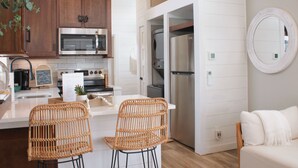 A modern kitchen with stainless steel appliances, wicker chairs, and a white dining area. - Riverfront Tiny House- Fishing & Kayaking (Strawberry Plains)