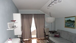 Una sala de estar moderna con un sofá gris, un mueble blanco, una mesa de centro de vidrio y un cuadro en la pared.