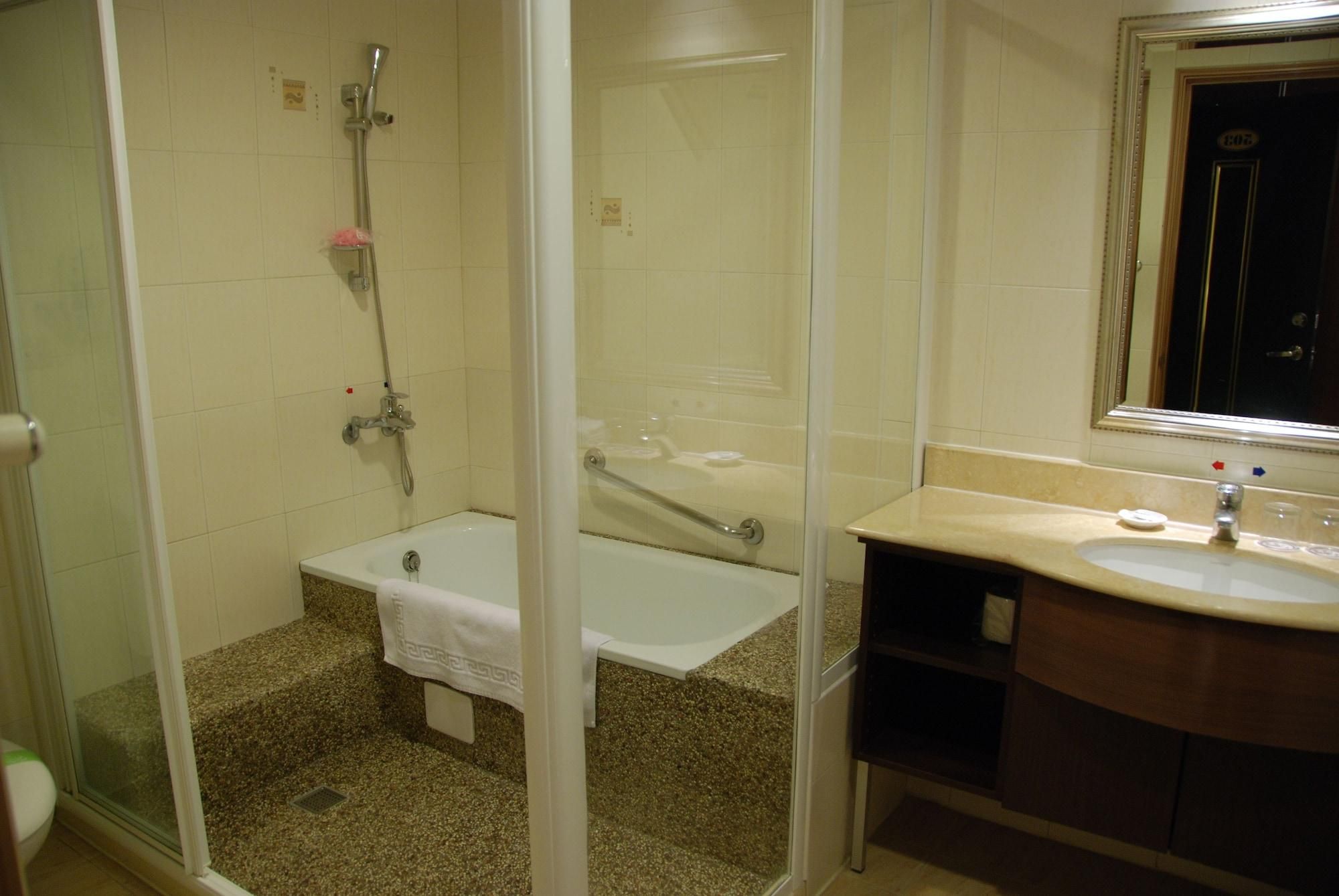 A bathroom with a glass-enclosed shower, a bathtub, and a vanity with a sink.