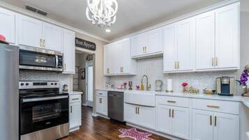 A modern kitchen with white cabinets, stainless steel appliances, and decorative items.