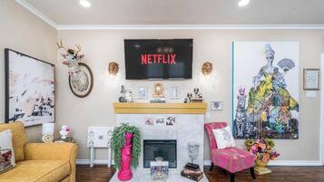 A living room with a fireplace, a mounted television, and various decorative items.