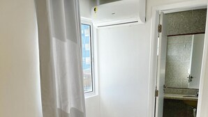A hotel room with a bed, a bathroom visible through an open door, and an air conditioning unit on the wall. - Cond. Azul Mar Porto de Galinhas (Ipojuca)