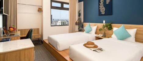 A hotel room with two beds, a desk, a laptop, and a view of the city.
