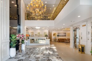 Een hotel lobby met een grote kroonluchter, een receptiebalie en een hoge plafond.