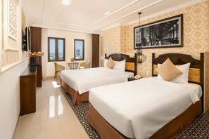 Une chambre d’hôtel avec deux lits, un bureau, une chaise et une grande fenêtre.