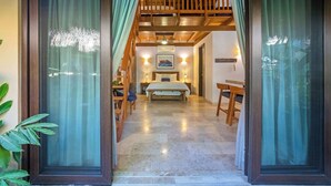 A hotel room with a bed, wooden furniture, and a view through a large window. - Villa Tayrona (Bucerías)