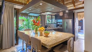 A modern kitchen with a large island, bar stools, and a dining area. - Villa Tayrona (Bucerías)