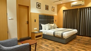 Camera d'albergo con un letto, un comodino, una sedia, una ventola a soffitto e un condizionatore.