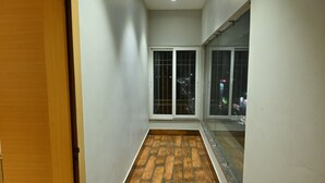 Un corridoio stretto con pavimento in legno, una porta scorrevole in vetro e vista sulla città di notte.