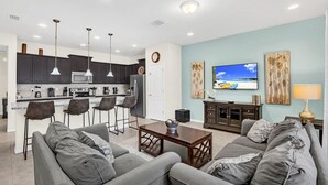 Una sala de estar moderna con un sofá gris, una mesa de centro y un televisor montado en la pared.
