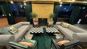 Un espace salon confortable avec des canapés, une table basse à carreaux et des fauteuils verts.