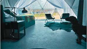 Une pièce aménagée comme une tente, avec un lit, un bureau, deux chaises et une petite piscine.