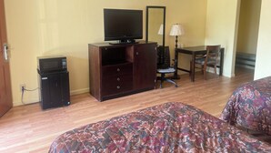A hotel room with two beds, a television, a desk with a chair, a lamp, and a microwave. - Economy Inn San Marco (Jacksonville)