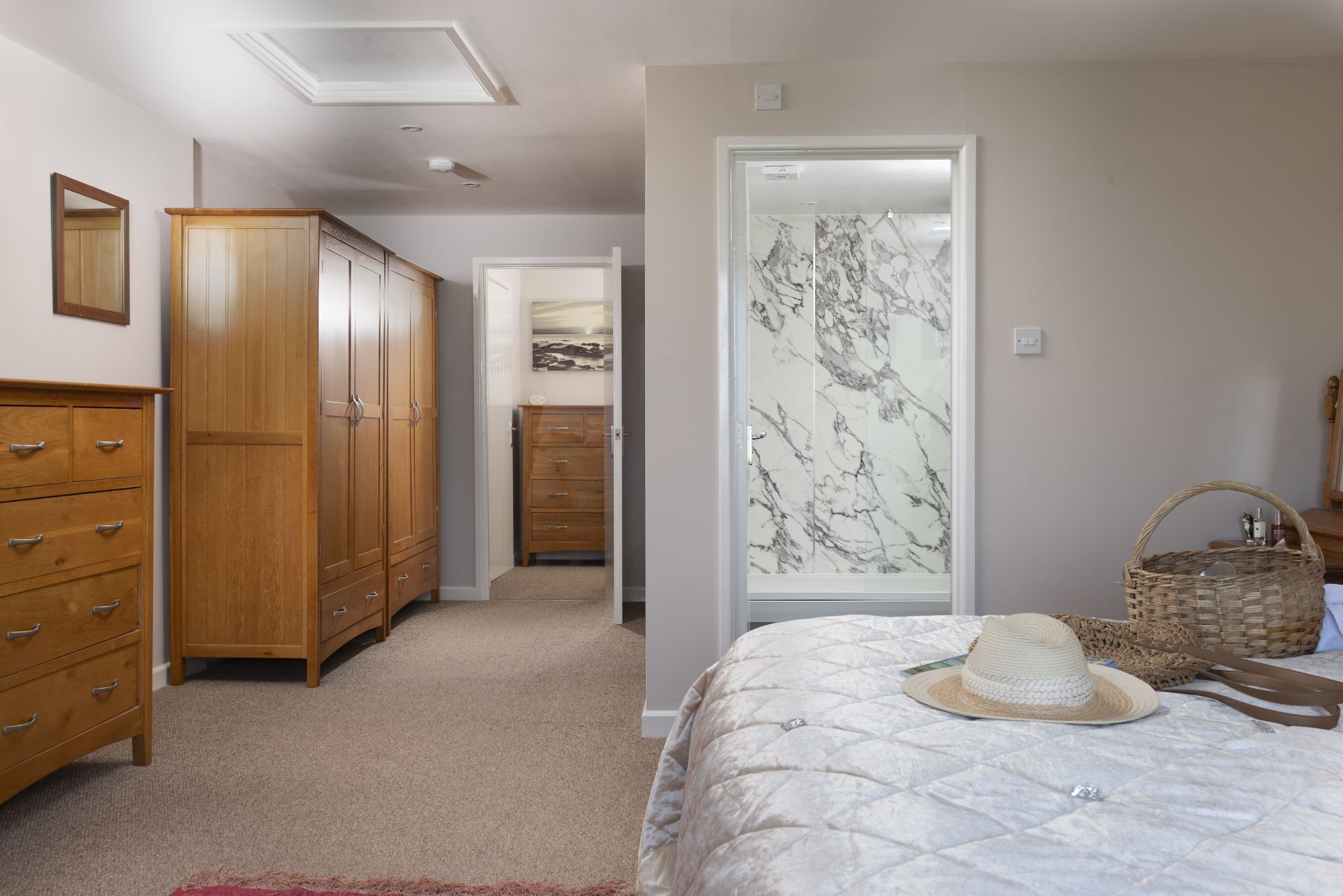 Een slaapkamer met een bed, een houten garderobe en een badkamer met een marmeren douche.