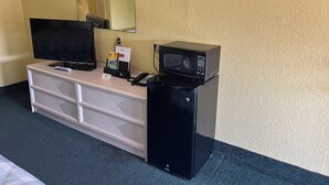 A hotel room with a desk, a television, a microwave, and a small refrigerator. - Antler's Inn (Cuero)