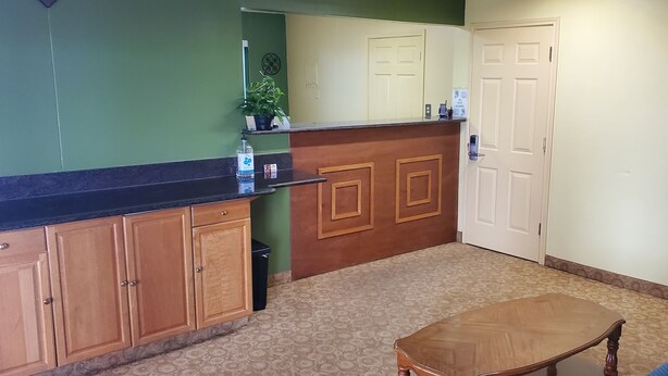 A small, clean room with a wooden cabinet, a small table, and a blue chair. - Antler's Inn (Cuero)