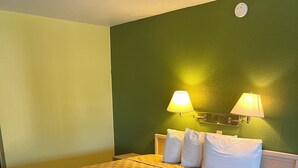 A hotel room with a large bed, two bedside lamps, and a small table. - Antler's Inn (Cuero)