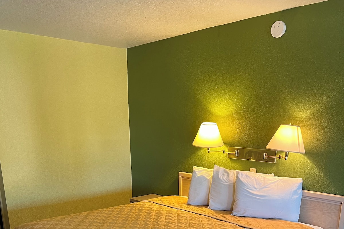 A hotel room with a large bed, two bedside lamps, and a small table.