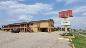 A two-story building with a sign reading "Antlers Inn" and a welcome sign. - Antler's Inn (Cuero)