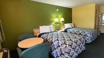A hotel room with two beds, a small round table, and a chair.