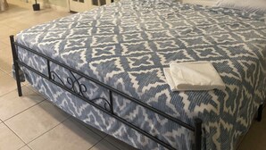 A neatly made bed with a patterned bedspread, a nightstand with a lamp, and a door leading to another room. - Delightful Atlanta family- sized apt. Sleeps 6 & pet friendly. (Atlanta)