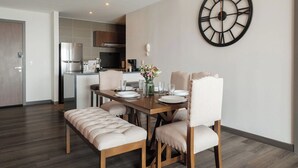 Un espace repas moderne avec une table en bois dressée pour quatre personnes, un banc et une grande horloge murale.