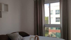 Habitación de hotel con cama, ventana con cortinas y vista a un edificio.