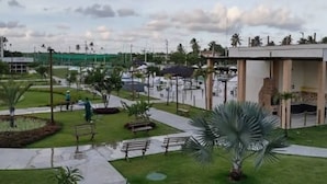 Un parque con bancos, palmeras y un edificio de fachada de piedra.