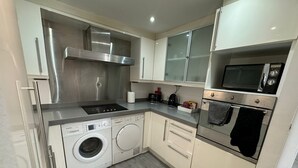 A compact kitchen with a Bosch washing machine, a microwave, a stove, and a built-in oven. - Luxury Loft Style 2 Bed Apartment Next to Excel/o2 (London)