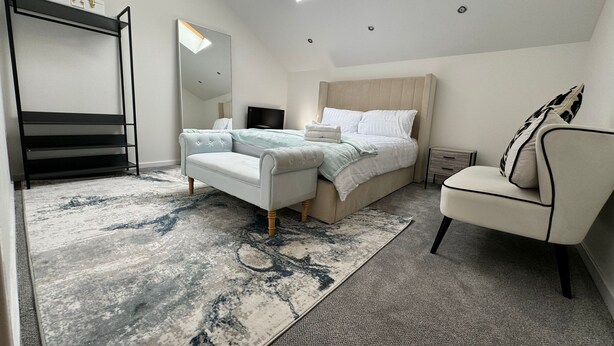 A modern bedroom with a loft bed, a seating area, a vanity, and a skylight. - Luxury Loft Style 2 Bed Apartment Next to Excel/o2 (London)