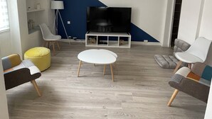 Moderni olohuone, jossa on litteänäyttöinen televisio, valkoinen sohvapöytä ja sininen tehosteseinä.