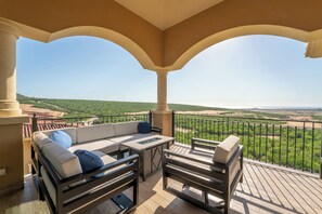 Un balcón con sofá y sillones, con vistas a un paisaje verde.