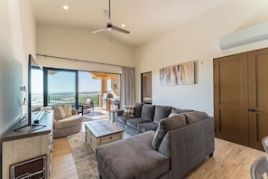 A spacious living room with a large gray sectional sofa, a wooden coffee table, and a television on a stand.