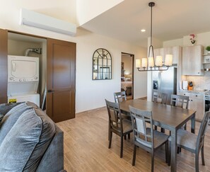 A modern kitchen with wooden cabinets, a built-in oven, and a dining area with a wooden table and chairs.