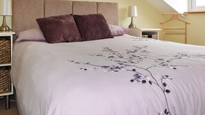 A neatly made bed with a floral bedspread, two pillows, and a headboard. - 1 bedroom accommodation in Ventnor (Ventnor)