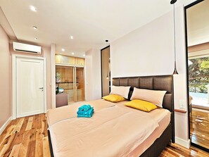 Une chambre moderne avec un grand lit, un plancher en bois et une vue sur un jardin, accessible par une porte coulissante.