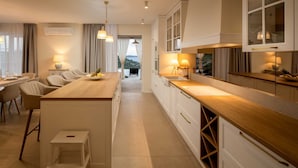 Een moderne keuken met een centraal eiland, witte kasten en hanglampen.