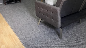 Un salon moderne avec un canapé gris, un téléviseur à écran plat et un coin repas comprenant une petite table et des chaises.