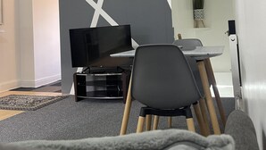 Un salon moderne avec un téléviseur à écran plat, une table à manger et un canapé gris.