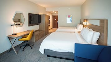 A hotel room with a bed, a desk with a chair, a TV, and a mirror.