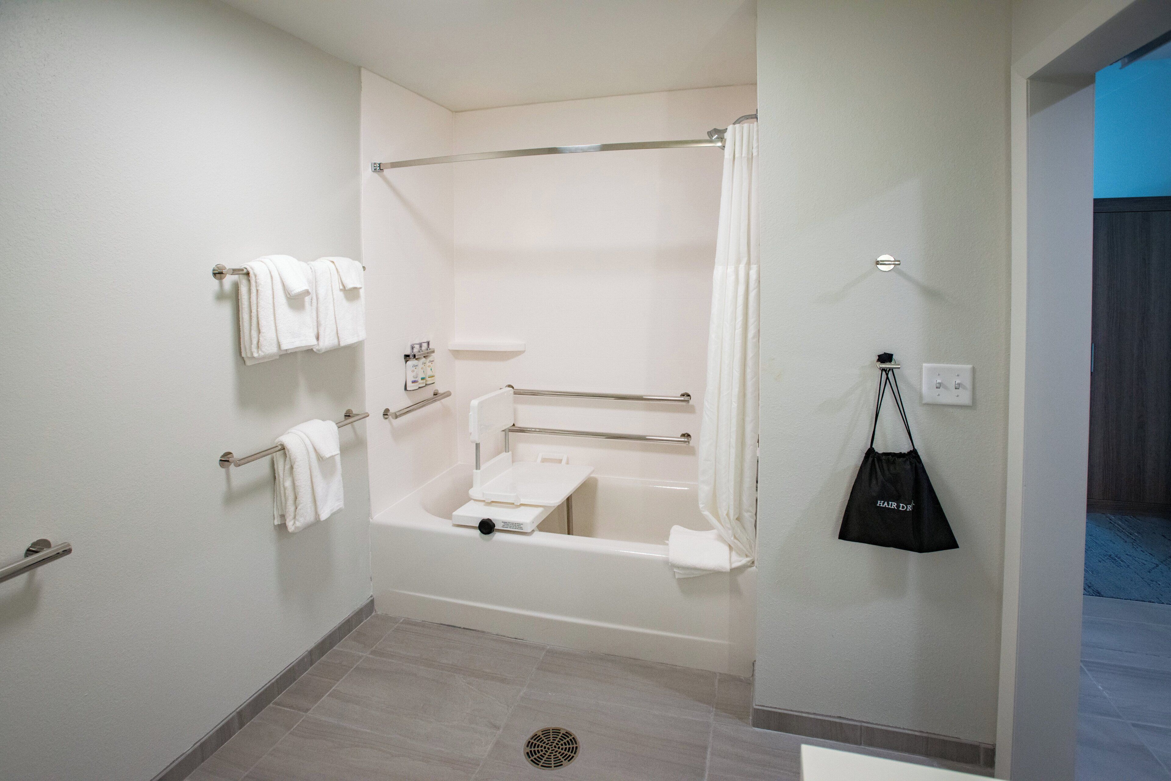 Un baño con una bañera, cortina de ducha y un toallero con varias toallas.