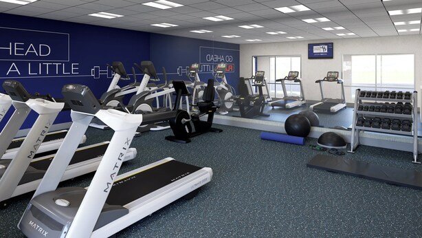 Un gimnasio con cintas de correr, elípticas y equipo de pesas.
