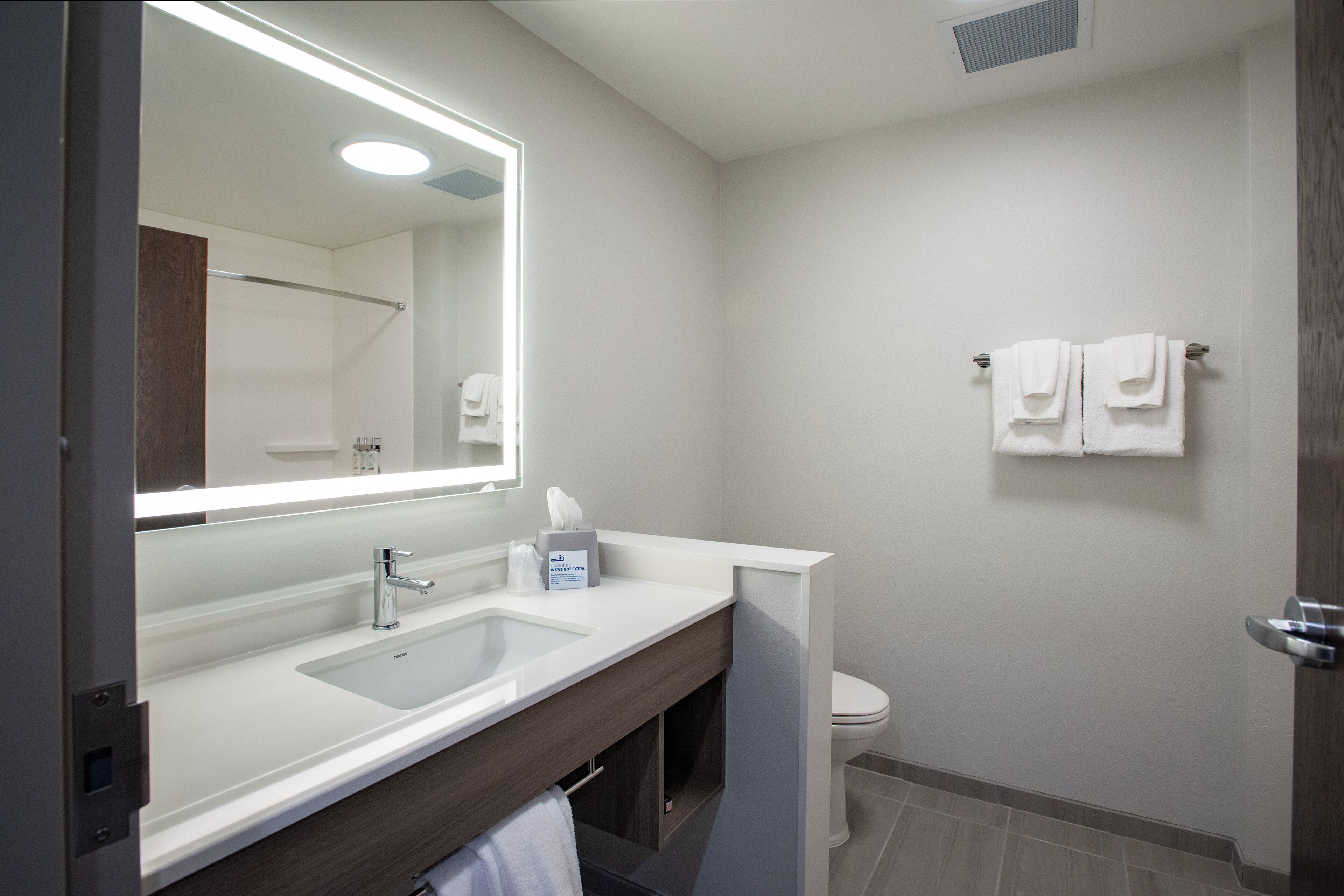 Un baño moderno con un espejo grande, un lavamanos y un inodoro.