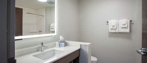A modern bathroom with a large mirror, a sink, and a toilet.
